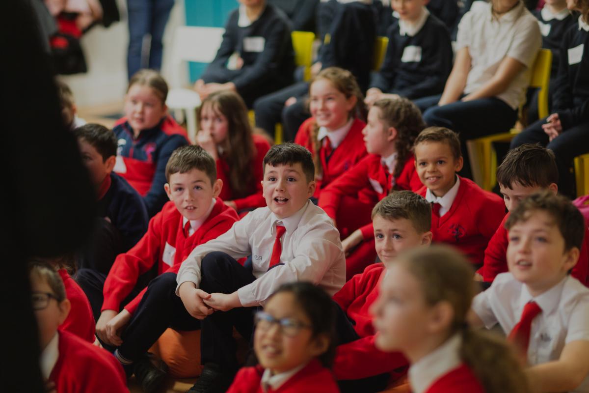 A group of primary school children smiling at a workshop leader.